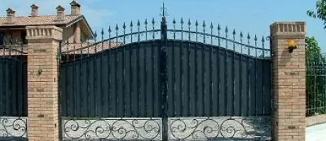 Cancello in ferro battuto motorizzato tra pilastri in mattoni a Torino